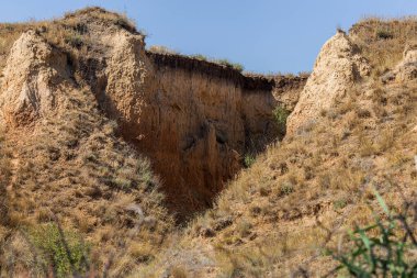 Çevreye zararlı bir bölgede dağ heyelan. Yeryüzündeki büyük çatlaklar, toprak yolu kapatan büyük katmanların inişi. Dağ yamacının yamacında baraj tehlikesi