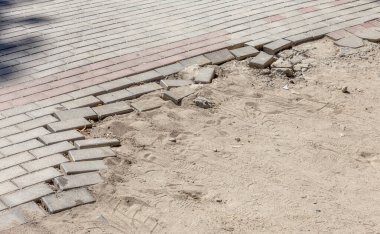 Kış boyunca buzların çözülmesinin yol açtığı çukurlu asfalt yol. Kötü yol. Yaya yolunda kırık kaldırım levhaları.