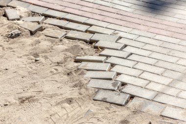 Kış boyunca buzların çözülmesinin yol açtığı çukurlu asfalt yol. Kötü yol. Yaya yolunda kırık kaldırım levhaları.