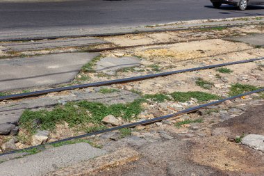 Çukurlu asfalt yolda hasar var. Kötü yol, kötü asfalt. Tramvay rayları, çatlaklar, çukurlar, asfalt çukurları olan bozuk bir yol.