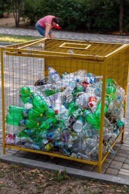 ODESSA, UKRAINE -CIRKA 2017: Boş kullanılmış plastik şişeler plastik atık ve geri dönüşüm için özel bir ağ metal kapta toplanır