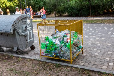 ODESSA, UKRAINE -CIRKA 2017: Boş kullanılmış plastik şişeler plastik atık ve geri dönüşüm için özel bir ağ metal kapta toplanır