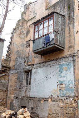 Eski evin balkonundaki çamaşır ipinde yıkandıktan sonra temiz çarşaflar kurur. Çamaşır ipinde yıkanmış kuru giysileri olan eski bir evin balkonunda.