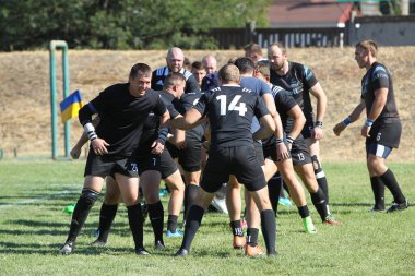 Odessa, Ukrayna - 29 Ağustos 2020: Odessa Milli Takımı CREDO (kırmızı) - Kiev Antares (siyah) ragbi 7 'leri. Top için erkek rugby oyuncularının sert agresif dövüşü. Stadyumun yeşil çimenlik alanında dinamik bir oyun