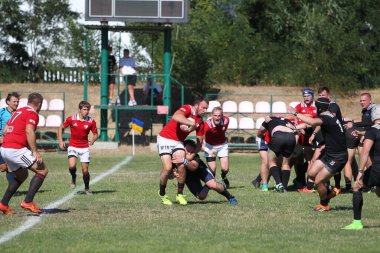 Odessa, Ukrayna - 29 Ağustos 2020: Odessa Milli Takımı CREDO (kırmızı) - Kiev Antares (siyah) ragbi 7 'leri. Top için erkek rugby oyuncularının sert agresif dövüşü. Stadyumun yeşil çimenlik alanında dinamik bir oyun