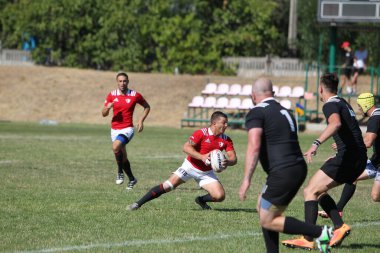 Odessa, Ukrayna - 29 Ağustos 2020: Odessa Milli Takımı CREDO (kırmızı) - Kiev Antares (siyah) ragbi 7 'leri. Top için erkek rugby oyuncularının sert agresif dövüşü. Stadyumun yeşil çimenlik alanında dinamik bir oyun