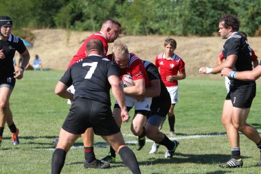 Odessa, Ukrayna - 29 Ağustos 2020: Odessa Milli Takımı CREDO (kırmızı) - Kiev Antares (siyah) ragbi 7 'leri. Top için erkek rugby oyuncularının sert agresif dövüşü. Stadyumun yeşil çimenlik alanında dinamik bir oyun