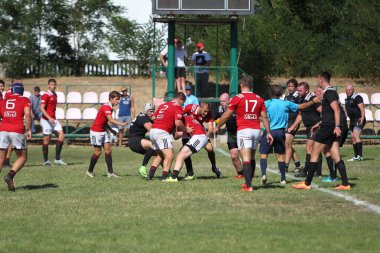 Odessa, Ukrayna - 29 Ağustos 2020: Odessa Milli Takımı CREDO (kırmızı) - Kiev Antares (siyah) ragbi 7 'leri. Top için erkek rugby oyuncularının sert agresif dövüşü. Stadyumun yeşil çimenlik alanında dinamik bir oyun