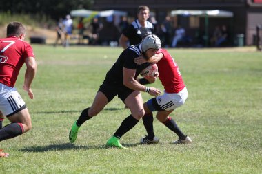 Odessa, Ukrayna - 29 Ağustos 2020: Odessa Milli Takımı CREDO (kırmızı) - Kiev Antares (siyah) ragbi 7 'leri. Top için erkek rugby oyuncularının sert agresif dövüşü. Stadyumun yeşil çimenlik alanında dinamik bir oyun