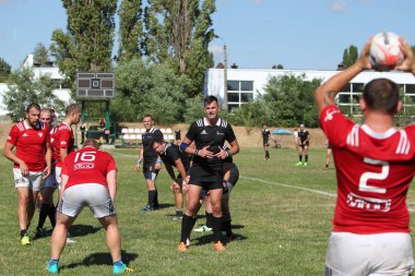 Odessa, Ukrayna - 29 Ağustos 2020: Odessa Milli Takımı CREDO (kırmızı) - Kiev Antares (siyah) ragbi 7 'leri. Top için erkek rugby oyuncularının sert agresif dövüşü. Stadyumun yeşil çimenlik alanında dinamik bir oyun