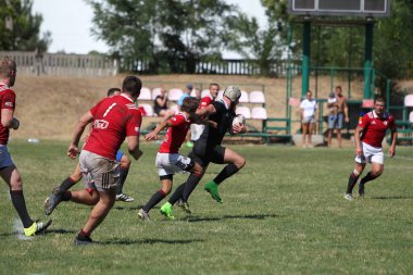 Odessa, Ukrayna - 29 Ağustos 2020: Odessa Milli Takımı CREDO (kırmızı) - Kiev Antares (siyah) ragbi 7 'leri. Top için erkek rugby oyuncularının sert agresif dövüşü. Stadyumun yeşil çimenlik alanında dinamik bir oyun