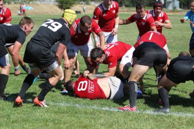 Odessa, Ukrayna - 29 Ağustos 2020: Odessa Milli Takımı CREDO (kırmızı) - Kiev Antares (siyah) ragbi 7 'leri. Top için erkek rugby oyuncularının sert agresif dövüşü. Stadyumun yeşil çimenlik alanında dinamik bir oyun