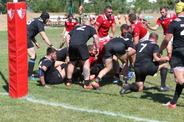 Odessa, Ukrayna - 29 Ağustos 2020: Odessa Milli Takımı CREDO (kırmızı) - Kiev Antares (siyah) ragbi 7 'leri. Top için erkek rugby oyuncularının sert agresif dövüşü. Stadyumun yeşil çimenlik alanında dinamik bir oyun