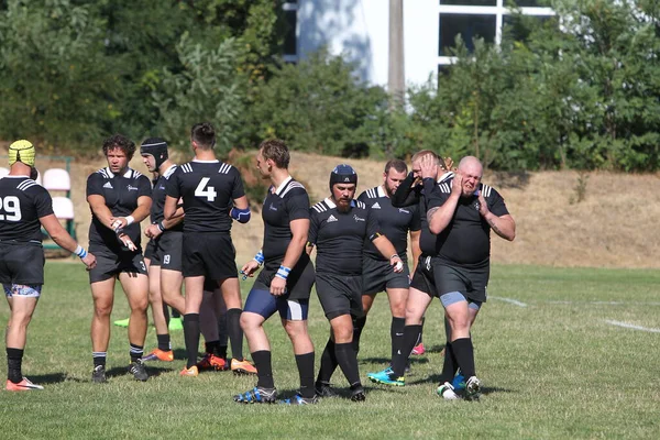 Odessa, Ukrayna - 29 Ağustos 2020: Odessa Milli Takımı CREDO (kırmızı) - Kiev Antares (siyah) ragbi 7 'leri. Top için erkek rugby oyuncularının sert agresif dövüşü. Stadyumun yeşil çimenlik alanında dinamik bir oyun