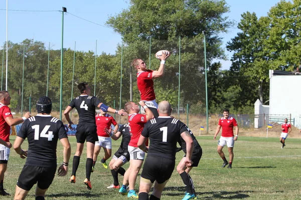 Odessa, Ukrayna - 29 Ağustos 2020: Odessa Milli Takımı CREDO (kırmızı) - Kiev Antares (siyah) ragbi 7 'leri. Top için erkek rugby oyuncularının sert agresif dövüşü. Stadyumun yeşil çimenlik alanında dinamik bir oyun