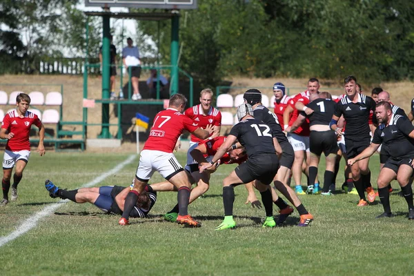 Odessa, Ukrayna - 29 Ağustos 2020: Odessa Milli Takımı CREDO (kırmızı) - Kiev Antares (siyah) ragbi 7 'leri. Top için erkek rugby oyuncularının sert agresif dövüşü. Stadyumun yeşil çimenlik alanında dinamik bir oyun