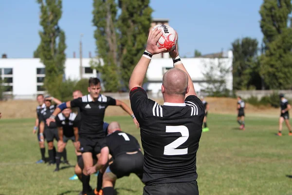 Odessa, Ukrayna - 29 Ağustos 2020: Odessa Milli Takımı CREDO (kırmızı) - Kiev Antares (siyah) ragbi 7 'leri. Top için erkek rugby oyuncularının sert agresif dövüşü. Stadyumun yeşil çimenlik alanında dinamik bir oyun