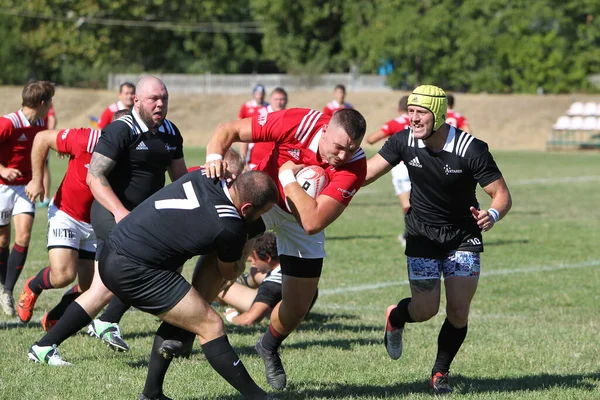Odessa, Ukrayna - 29 Ağustos 2020: Odessa Milli Takımı CREDO (kırmızı) - Kiev Antares (siyah) ragbi 7 'leri. Top için erkek rugby oyuncularının sert agresif dövüşü. Stadyumun yeşil çimenlik alanında dinamik bir oyun