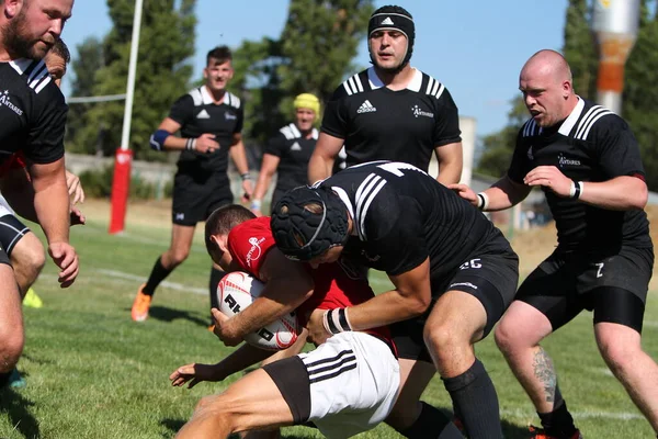 Odessa, Ukrayna - 29 Ağustos 2020: Odessa Milli Takımı CREDO (kırmızı) - Kiev Antares (siyah) ragbi 7 'leri. Top için erkek rugby oyuncularının sert agresif dövüşü. Stadyumun yeşil çimenlik alanında dinamik bir oyun
