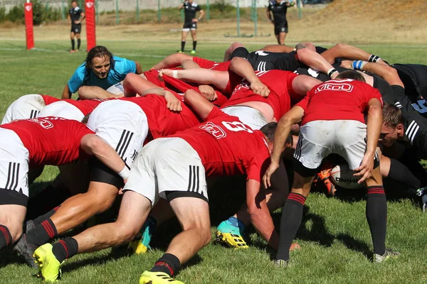 Odessa, Ukrayna - 29 Ağustos 2020: Odessa Milli Takımı CREDO (kırmızı) - Kiev Antares (siyah) ragbi 7 'leri. Top için erkek rugby oyuncularının sert agresif dövüşü. Stadyumun yeşil çimenlik alanında dinamik bir oyun