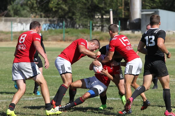 Odessa, Ukrayna - 29 Ağustos 2020: Odessa Milli Takımı CREDO (kırmızı) - Kiev Antares (siyah) ragbi 7 'leri. Top için erkek rugby oyuncularının sert agresif dövüşü. Stadyumun yeşil çimenlik alanında dinamik bir oyun