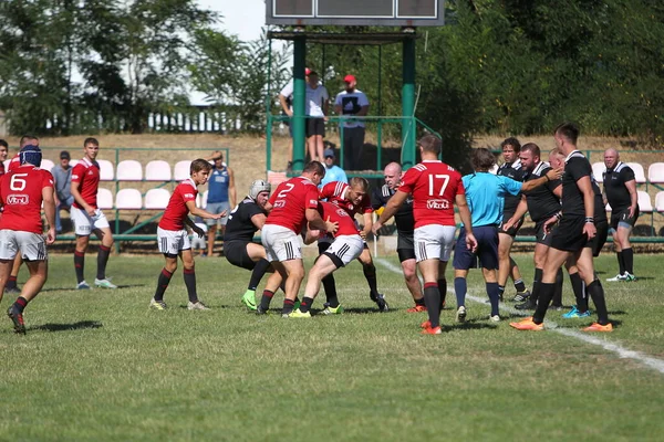 Odessa, Ukrayna - 29 Ağustos 2020: Odessa Milli Takımı CREDO (kırmızı) - Kiev Antares (siyah) ragbi 7 'leri. Top için erkek rugby oyuncularının sert agresif dövüşü. Stadyumun yeşil çimenlik alanında dinamik bir oyun