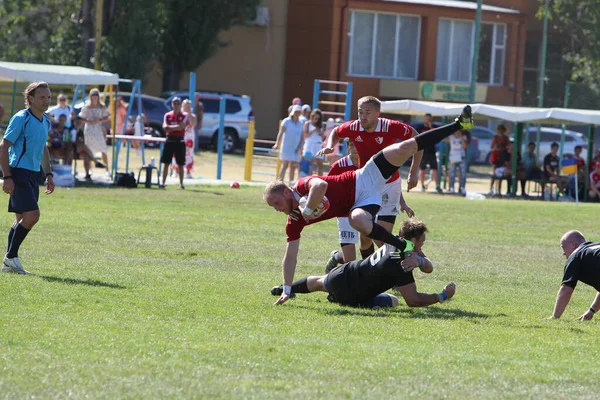 Odessa, Ukrayna - 29 Ağustos 2020: Odessa Milli Takımı CREDO (kırmızı) - Kiev Antares (siyah) ragbi 7 'leri. Top için erkek rugby oyuncularının sert agresif dövüşü. Stadyumun yeşil çimenlik alanında dinamik bir oyun