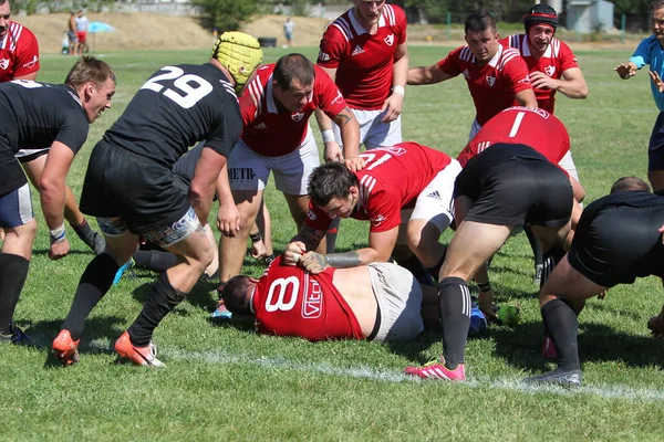 Odessa, Ukrayna - 29 Ağustos 2020: Odessa Milli Takımı CREDO (kırmızı) - Kiev Antares (siyah) ragbi 7 'leri. Top için erkek rugby oyuncularının sert agresif dövüşü. Stadyumun yeşil çimenlik alanında dinamik bir oyun