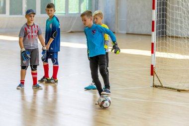 ODESSA, UKRAINE-CIRCA-2020: Çocuklar mini futbol oynuyor. Futsal kaleci kapıda duruyor. Futbolcuların, futsal kalecilerinin, futbol sahasındaki çocukların spor eğitimi.