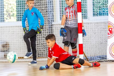 ODESSA, UKRAINE-CIRCA-2020: Çocuklar mini futbol oynuyor. Futsal kaleci kapıda duruyor. Futbolcuların, futsal kalecilerinin, futbol sahasındaki çocukların spor eğitimi.