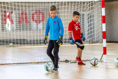 ODESSA, UKRAINE-CIRCA-2020: Çocuklar mini futbol oynuyor. Futsal kaleci kapıda duruyor. Futbolcuların, futsal kalecilerinin, futbol sahasındaki çocukların spor eğitimi.