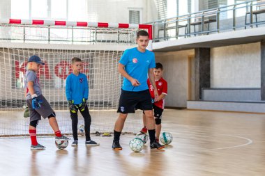 ODESSA, UKRAINE-CIRCA-2020: Çocuklar mini futbol oynuyor. Futsal kaleci kapıda duruyor. Futbolcuların, futsal kalecilerinin, futbol sahasındaki çocukların spor eğitimi.