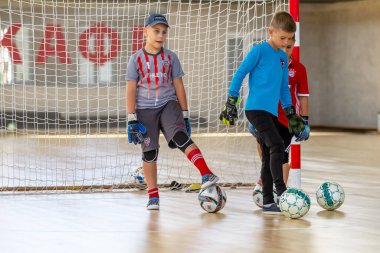 ODESSA, UKRAINE-CIRCA-2020: Çocuklar mini futbol oynuyor. Futsal kaleci kapıda duruyor. Futbolcuların, futsal kalecilerinin, futbol sahasındaki çocukların spor eğitimi.