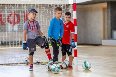 ODESSA, UKRAINE-CIRCA-2020: Çocuklar mini futbol oynuyor. Futsal kaleci kapıda duruyor. Futbolcuların, futsal kalecilerinin, futbol sahasındaki çocukların spor eğitimi.
