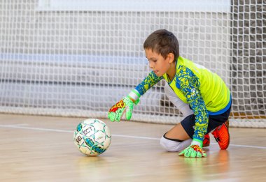 ODESSA, UKRAINE-CIRCA-2020: Çocuklar mini futbol oynuyor. Futsal kaleci kapıda duruyor. Futbolcuların, futsal kalecilerinin, futbol sahasındaki çocukların spor eğitimi.
