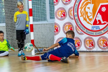 ODESSA, UKRAINE-CIRCA-2020: Çocuklar mini futbol oynuyor. Futsal kaleci kapıda duruyor. Futbolcuların, futsal kalecilerinin, futbol sahasındaki çocukların spor eğitimi.