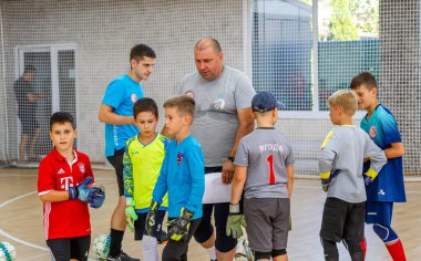 ODESSA, UKRAINE-CIRCA-2020: Çocuklar mini futbol oynuyor. Futsal kaleci kapıda duruyor. Futbolcuların, futsal kalecilerinin, futbol sahasındaki çocukların spor eğitimi.