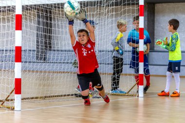 ODESSA, UKRAINE-CIRCA-2020: Çocuklar mini futbol oynuyor. Futsal kaleci kapıda duruyor. Futbolcuların, futsal kalecilerinin, futbol sahasındaki çocukların spor eğitimi.
