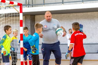 ODESSA, UKRAINE-CIRCA-2020: Çocuklar mini futbol oynuyor. Futsal kaleci kapıda duruyor. Futbolcuların, futsal kalecilerinin, futbol sahasındaki çocukların spor eğitimi.