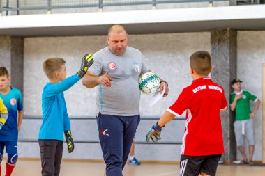 ODESSA, UKRAINE-CIRCA-2020: Çocuklar mini futbol oynuyor. Futsal kaleci kapıda duruyor. Futbolcuların, futsal kalecilerinin, futbol sahasındaki çocukların spor eğitimi.