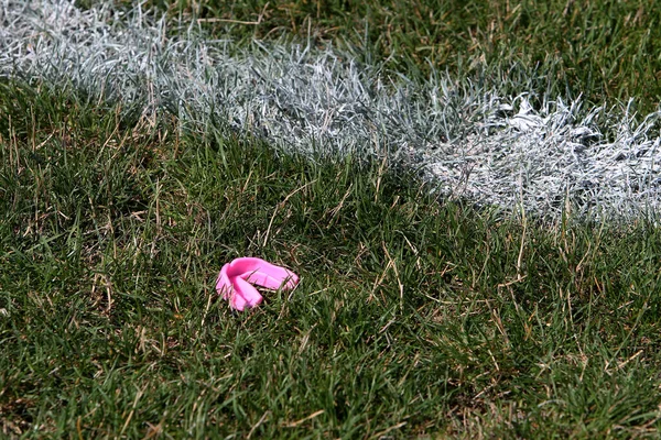 A sports silicone mouthguard to protect teeth during sports fights fell and lies on the green grass of the stadium field