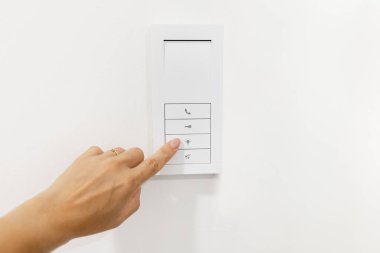 Hand pressing smart home wall control panel. Concept of modern technology, home automation, and digital lifestyle with connected devices and security features