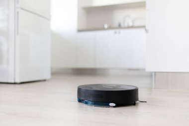 Siyah robot elektrikli süpürge mutfakta çalışıyor. Akıllı temizlik, otomasyon, kolaylık ve modern yaşam tarzı kavramı.