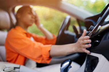 African American woman in car, stressed and touching forehead while adjusting air vent. Concept of fatigue, heat, and lifestyle discomfort while driving