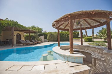 Lüks villa gösterisinde eve tropikal yaz yüzme havuz bar ile resort tatil ve sandalyeler güneş