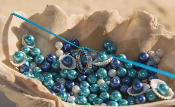 白い金の結婚指輪リングのペアが貝殻ロマンチックな熱帯のビーチ式で青いリボンに掛け — ストック写真