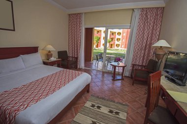 Maiyet-in balkon ve perdeler ile bir lüks otel odasında çift kişilik yatak