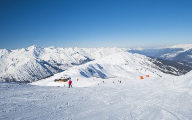 Skiers on a piste in alpine ski resort clipart