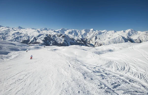 Sciatori su una pista in località sciistica alpina Foto Stock Royalty Free