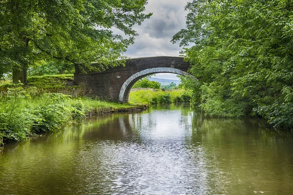 View of a British canal in rural setting with stone bridge — Stock Photo, Image